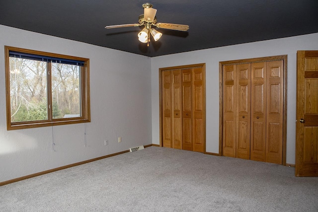 unfurnished bedroom with carpet, ceiling fan, and multiple closets