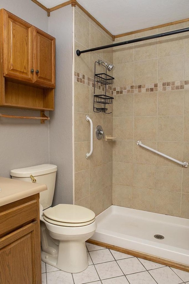 bathroom featuring tile patterned floors, a tile shower, vanity, crown molding, and toilet