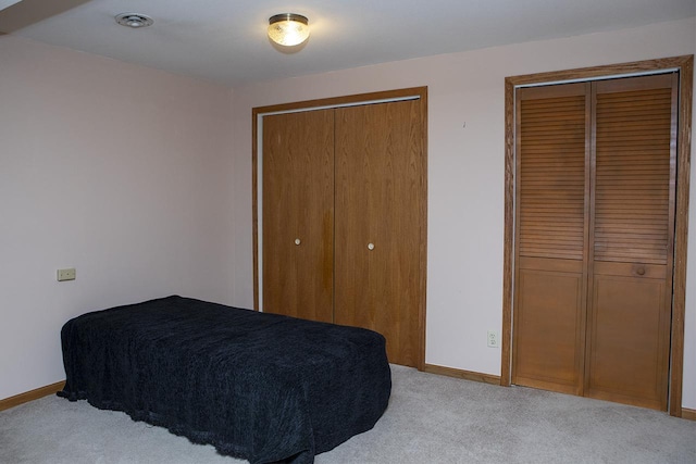 bedroom with light colored carpet and multiple closets