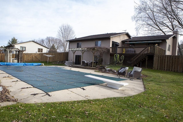 view of swimming pool featuring a diving board, a patio area, a yard, and a wooden deck