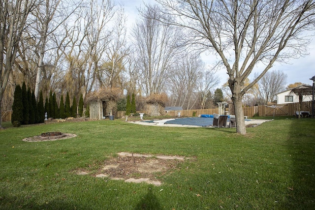 view of yard with a covered pool, a fire pit, and a storage unit