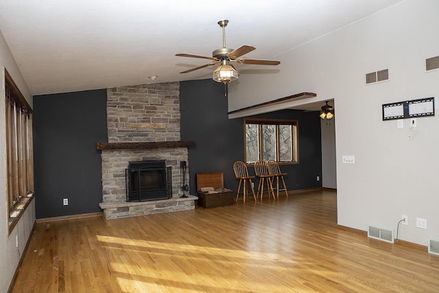 unfurnished living room with ceiling fan, a fireplace, lofted ceiling, and light wood-type flooring