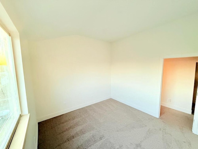 unfurnished room with vaulted ceiling and light colored carpet