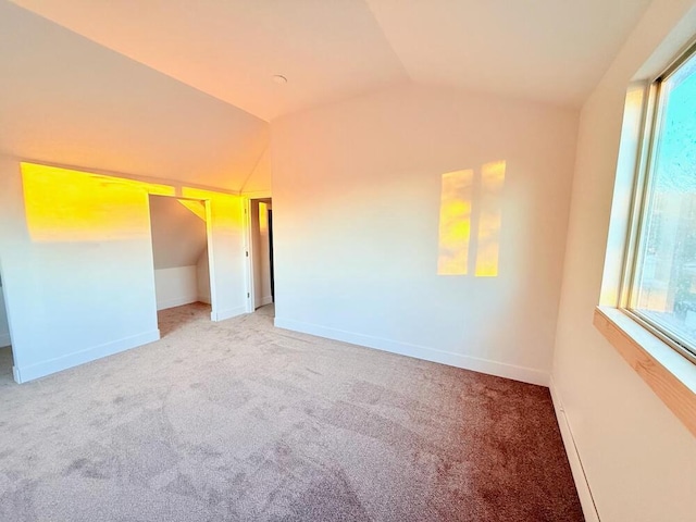 carpeted empty room with lofted ceiling