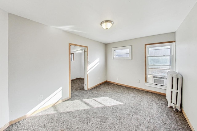 empty room with light colored carpet, cooling unit, and radiator heating unit