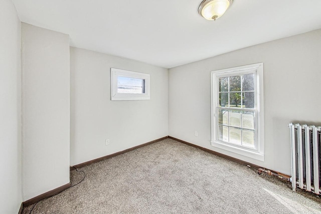 empty room featuring radiator, a healthy amount of sunlight, and light carpet