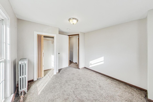 unfurnished bedroom featuring a closet, carpet, and radiator