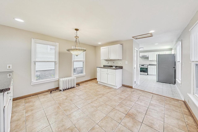 kitchen with radiator heating unit, light tile patterned floors, white cabinetry, appliances with stainless steel finishes, and decorative light fixtures