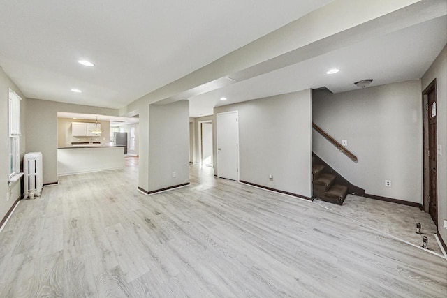 unfurnished living room featuring radiator heating unit and light hardwood / wood-style flooring