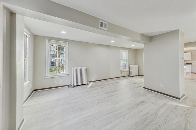 basement featuring light hardwood / wood-style floors and radiator