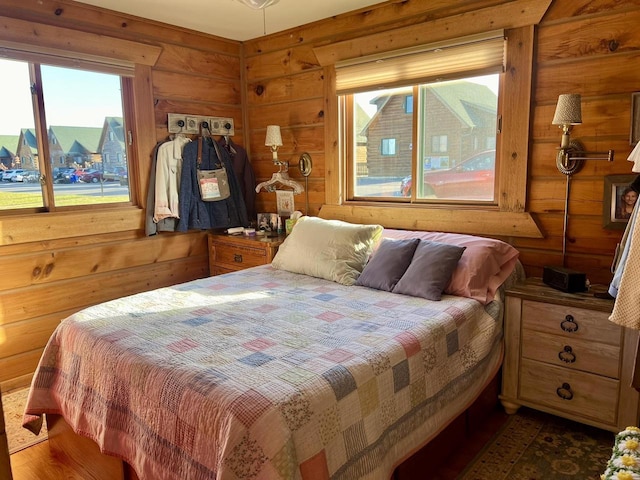 bedroom with wooden walls and dark hardwood / wood-style flooring