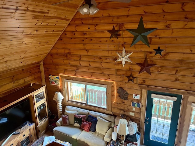 living room with wood walls, vaulted ceiling, and a healthy amount of sunlight