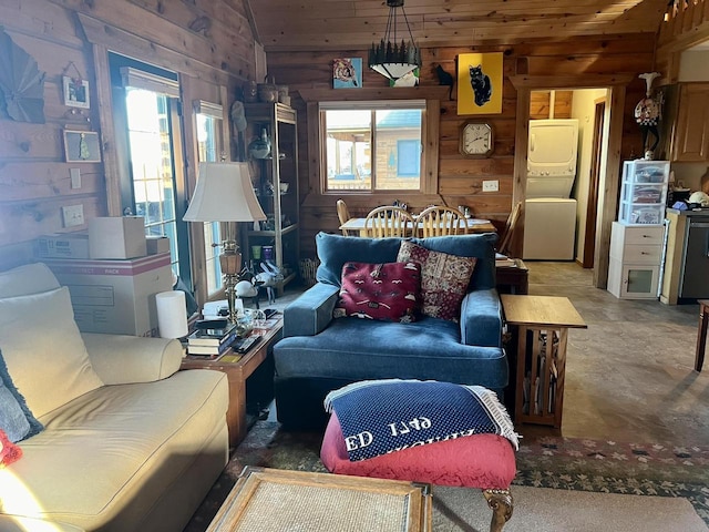 living room with concrete flooring, wooden walls, vaulted ceiling, and plenty of natural light