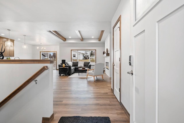 hallway with beamed ceiling, light wood-type flooring, and a chandelier