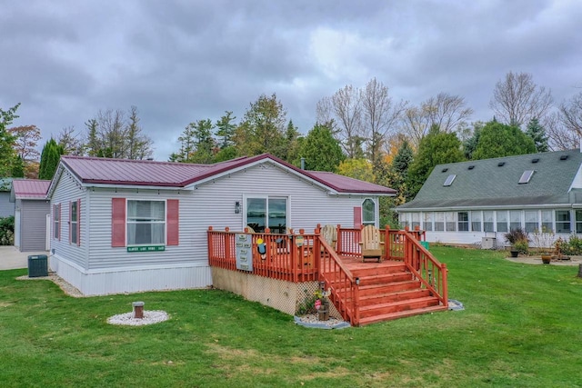 back of property with a wooden deck, a yard, and central AC unit