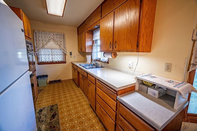 kitchen with black oven, sink, and white refrigerator