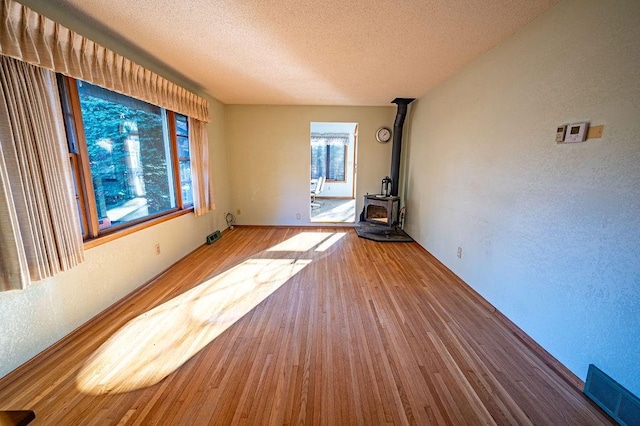 interior space featuring a textured ceiling, a wood stove, and wood-type flooring