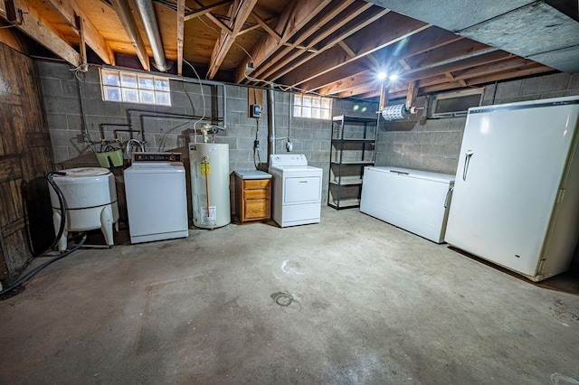 basement with washing machine and clothes dryer, water heater, a healthy amount of sunlight, and white fridge