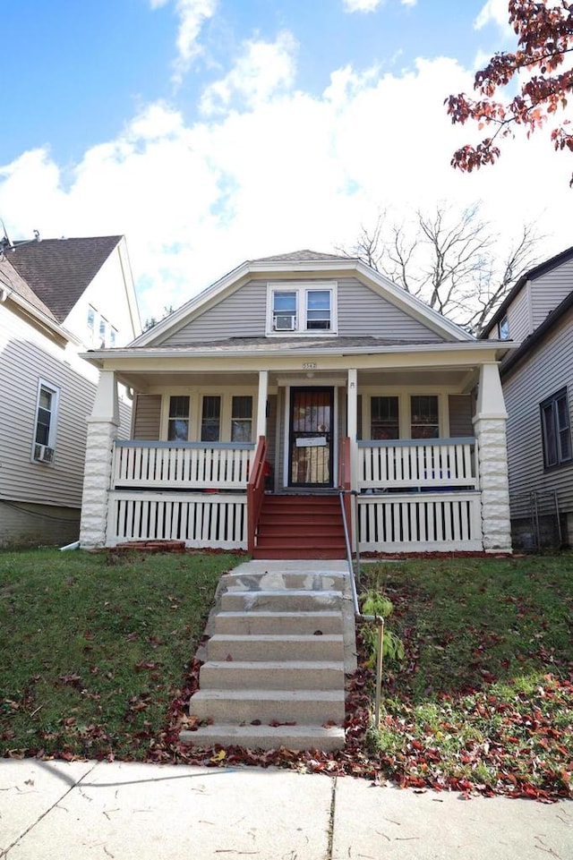 bungalow featuring covered porch and a front yard