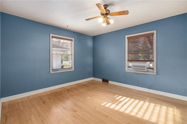 unfurnished room with a wealth of natural light, hardwood / wood-style flooring, and ceiling fan