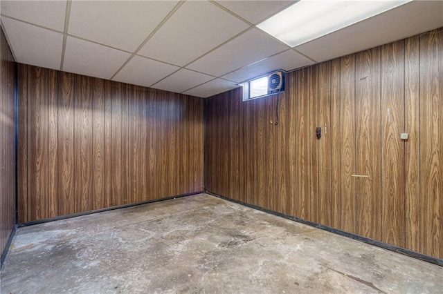 basement featuring wood walls and a paneled ceiling