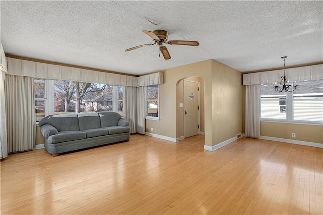 living room featuring ceiling fan with notable chandelier, a textured ceiling, and light wood-type flooring