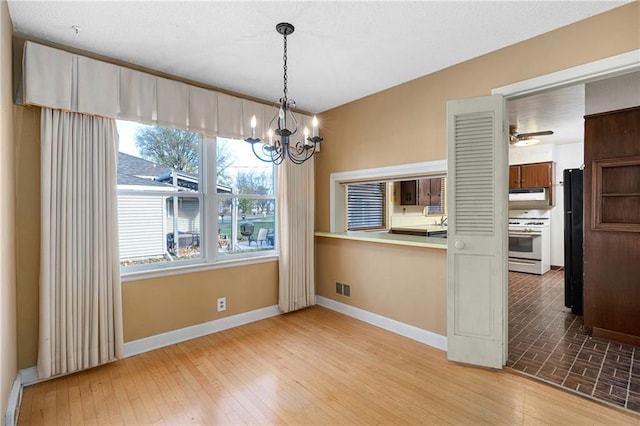 unfurnished dining area featuring light wood-type flooring and ceiling fan with notable chandelier