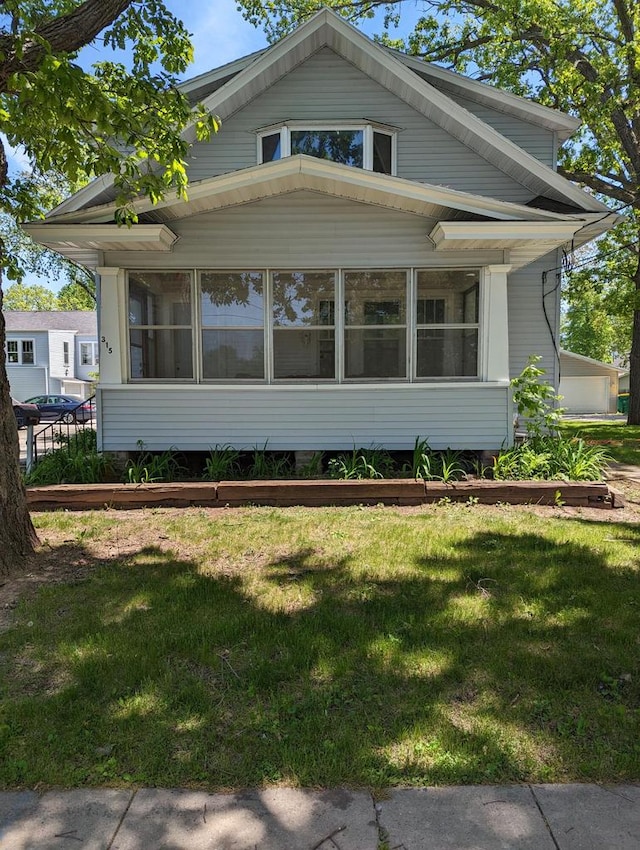 view of side of property featuring a lawn and a sunroom