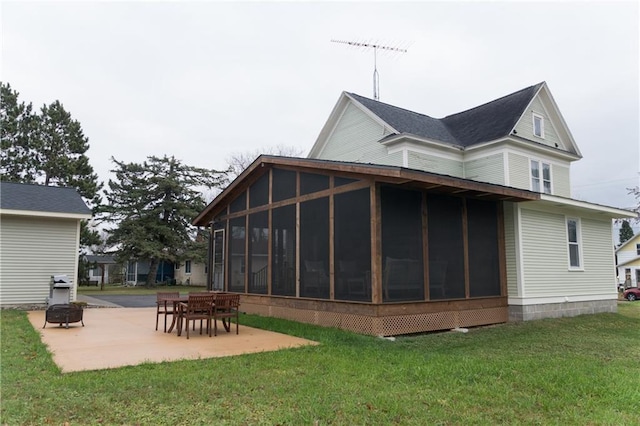 rear view of house with a sunroom, an outdoor fire pit, a yard, and a patio area