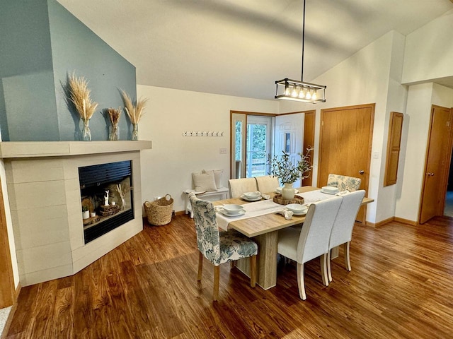 dining area with a fireplace, dark hardwood / wood-style flooring, and lofted ceiling