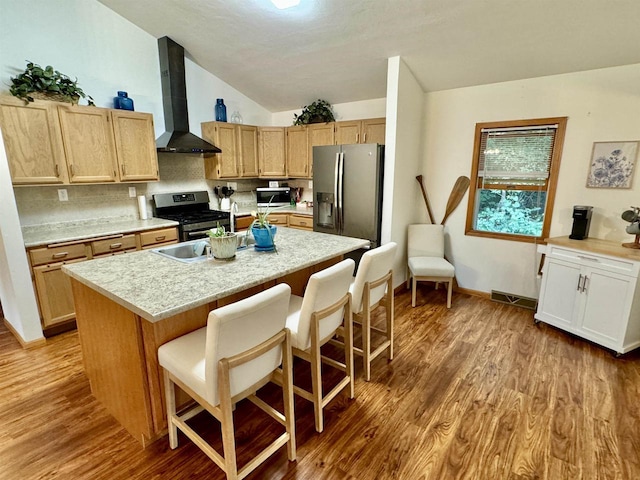 kitchen featuring a kitchen bar, appliances with stainless steel finishes, wood-type flooring, and wall chimney exhaust hood