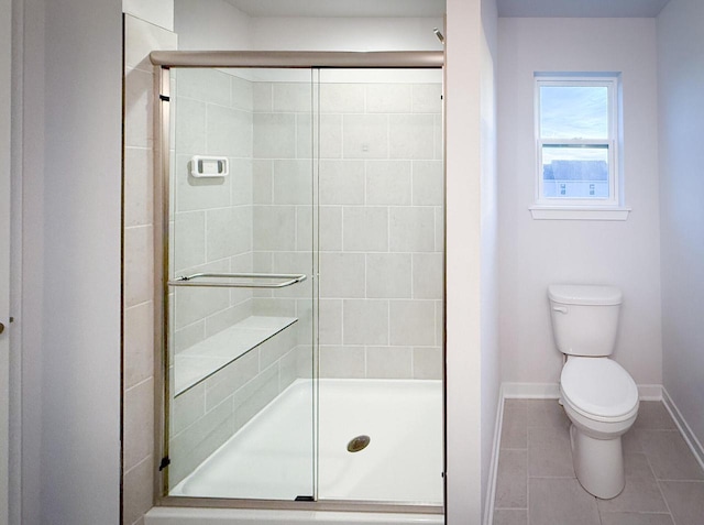 bathroom featuring toilet, tile patterned flooring, and a shower with door