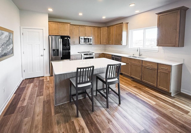 kitchen featuring a kitchen island, appliances with stainless steel finishes, sink, a breakfast bar, and dark wood-type flooring