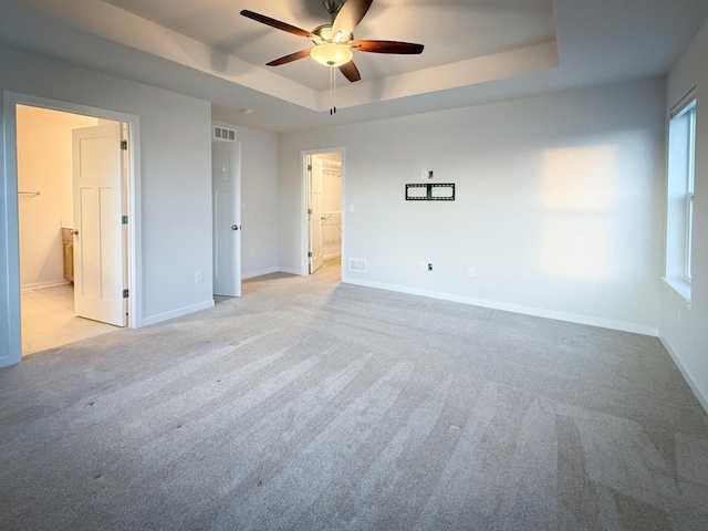 carpeted spare room with ceiling fan and a tray ceiling