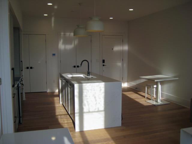 kitchen featuring pendant lighting, hardwood / wood-style flooring, sink, and an island with sink