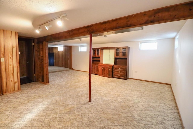 basement with track lighting, light carpet, and a textured ceiling