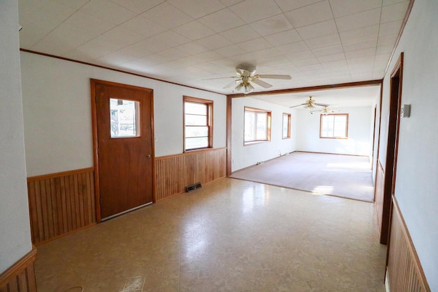 foyer entrance featuring ornamental molding, wood walls, and ceiling fan