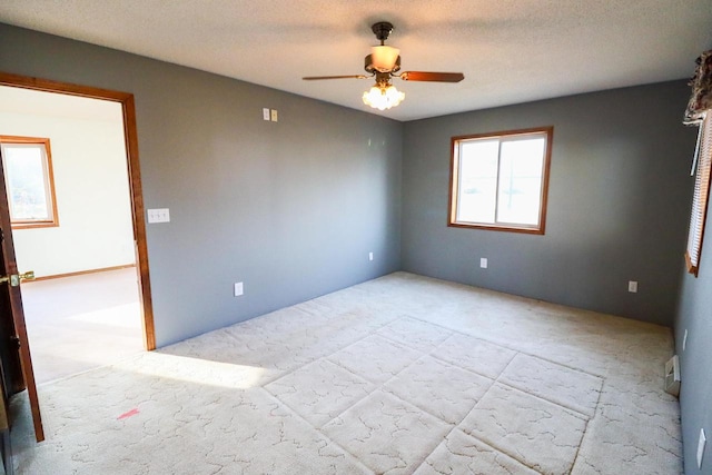 spare room featuring a textured ceiling, light carpet, and ceiling fan