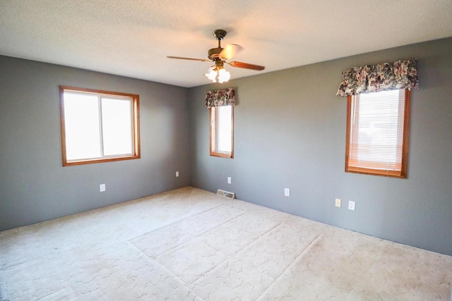 empty room with ceiling fan, a textured ceiling, and a healthy amount of sunlight