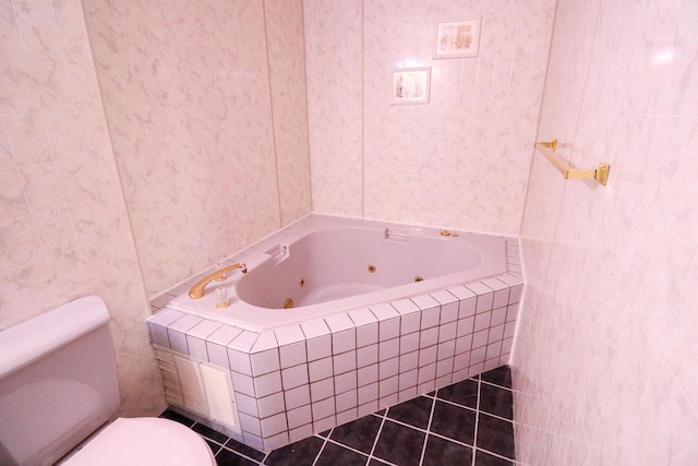 bathroom with tile patterned floors, toilet, tile walls, and tiled tub