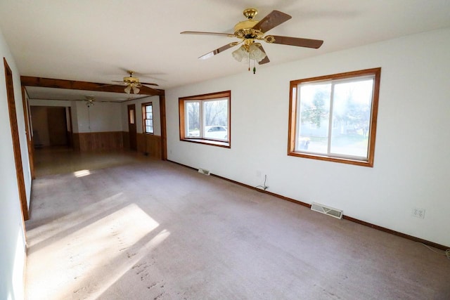 empty room featuring carpet floors, a healthy amount of sunlight, and ceiling fan