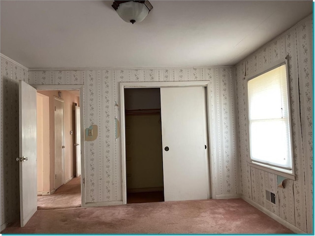 unfurnished bedroom with light colored carpet, a closet, and crown molding