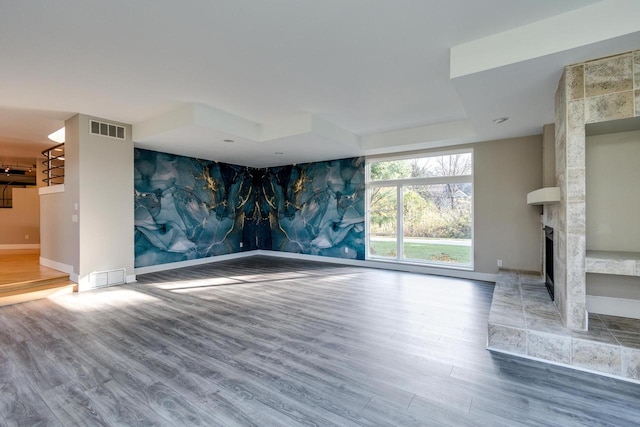 unfurnished living room with hardwood / wood-style floors and a tiled fireplace