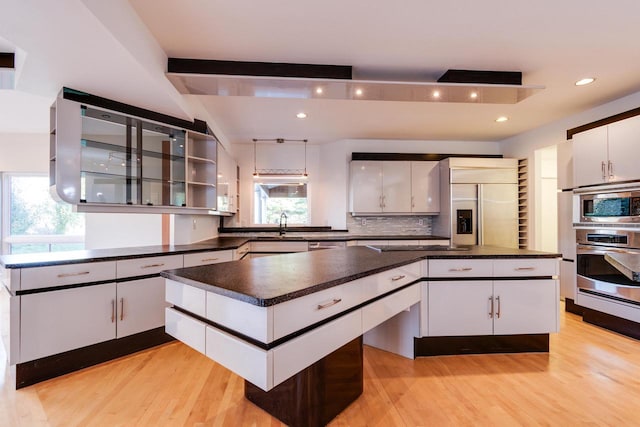 kitchen featuring a wealth of natural light, white cabinets, and light hardwood / wood-style floors