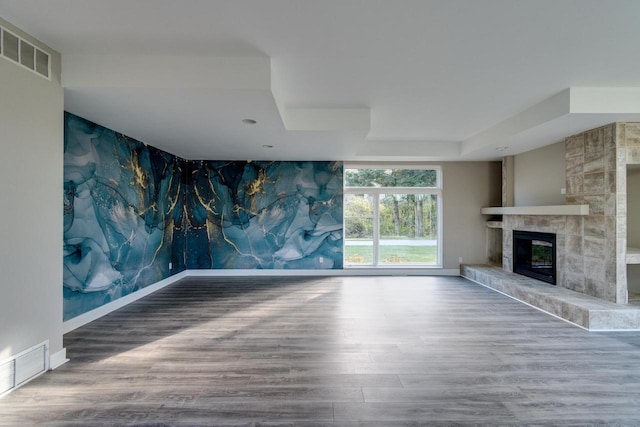 4720 Sumac Rd, Middleton, WI 53562 - unfurnished living room featuring an accent wall, wood finished floors, a stone fireplace, wallpapered walls, and a raised ceiling