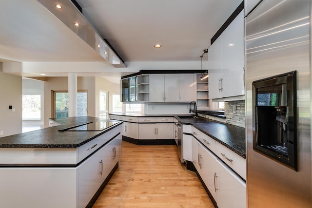 kitchen with white cabinets, black electric stovetop, tasteful backsplash, a center island, and light hardwood / wood-style floors