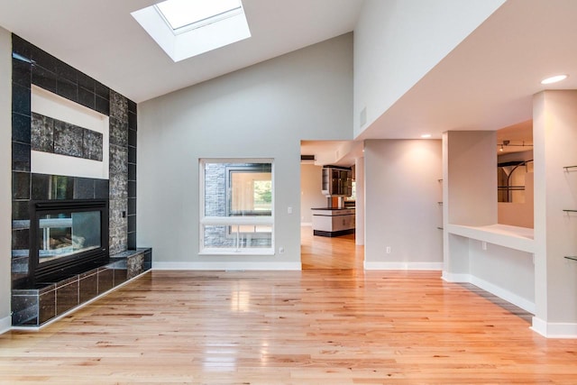 unfurnished living room with a fireplace, high vaulted ceiling, and light wood-type flooring