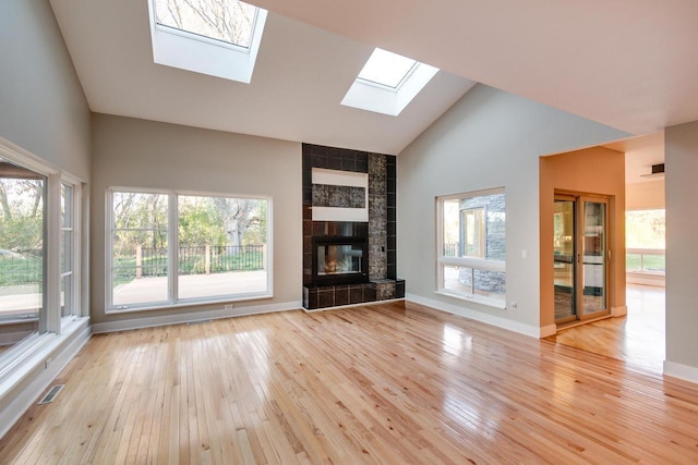 4720 Sumac Rd, Middleton, WI 53562 - unfurnished living room with a skylight, light wood-type flooring, plenty of natural light, high vaulted ceiling, and a fireplace