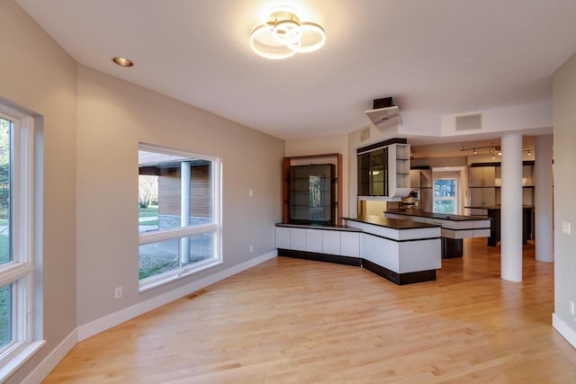 kitchen with light hardwood / wood-style flooring, kitchen peninsula, and a wealth of natural light