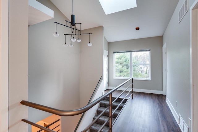 stairway featuring hardwood / wood-style floors and vaulted ceiling with skylight